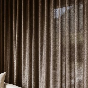 Sfeerfoto van linnen-lurex gordijnen in taupe, elegant vallend in een stijlvol ingerichte woonruimte.