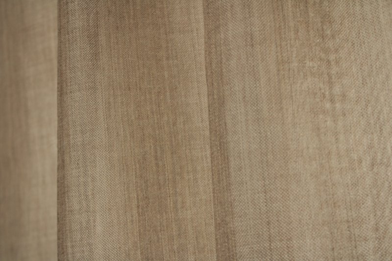 Sfeerfoto van beige inbetween gordijn Norena een luchtige stof in natuurlijke tint met zachte lichtinval voor een rustige uitstraling.