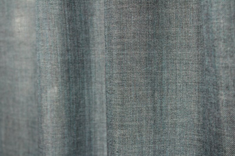 Sfeerfoto van blauwe inbetween gordijnen Norena een licht doorlatende stof in diepe blauwtint met elegante plooival.