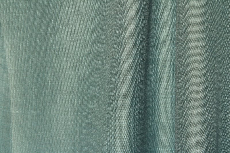 Sfeerfoto van de blauwe inbetween gordijnen met linnen look uit de Saphira Light collectie van Okika, natuurlijk hangend en zacht licht filterend voor een rustige uitstraling.