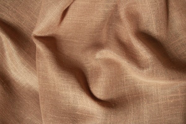 Gedraaid stofpatroon van de honingkleurige inbetween gordijnen met linnen look uit de Saphira Light collectie van Okika, met zicht op de natuurlijke weving en warme textuur.