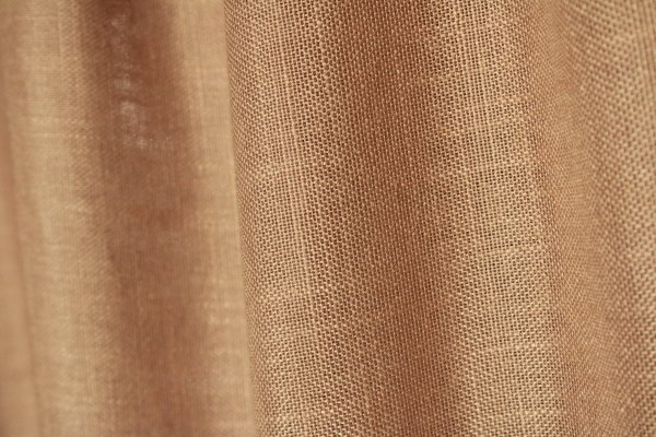 Stofdetails van de honingkleurige inbetween gordijnen met linnen look uit de Saphira Light collectie van Okika, met zicht op de luchtige structuur en warme uitstraling.