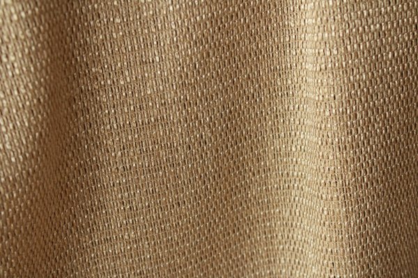 Beige inbetween gordijn Linea met grove weving. close up licht metallic glinstering in de stof