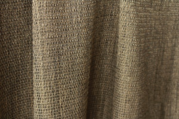 Sfeerfoto van grijze inbetween gordijnen Linea met robuuste textuur en natuurlijk lichtinval. luxe uitstraling door het licht metallic effect dat in de stof zit