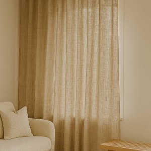 Inbetween gordijnen van 100% linnen in zandkleur, luchtig opgehangen in een interieur met warme, natuurlijke tinten.