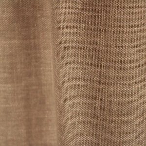 Sfeerfoto van de soft taupe inbetween gordijnen met linnen look uit de Saphira Light collectie van Okika, elegant hangend en zacht licht filterend voor een warme uitstraling.