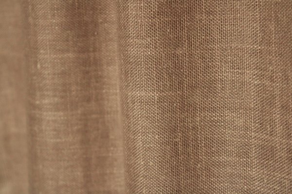Sfeerfoto van de soft taupe inbetween gordijnen met linnen look uit de Saphira Light collectie van Okika, elegant hangend en zacht licht filterend voor een warme uitstraling.