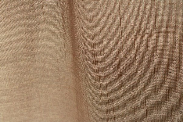 Stofstructuur van de soft taupe inbetween gordijnen met linnen look uit de Saphira Light collectie van Okika, lichtdoorlatend met subtiele natuurlijke vezelstructuur.