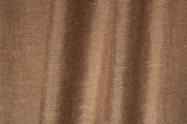 Sfeerfoto van taupekleurige inbetween gordijnen met linnen look uit de Saphira Light collectie van Okika, elegant hangend en lichtdoorlatend met een tijdloze uitstraling.