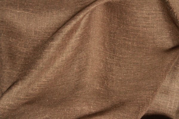 Gedraaid stofpatroon van de taupe kleurige inbetween gordijnen met linnen look uit de Saphira Light collectie van Okika, met zicht op de natuurlijke weving en zachte textuur.