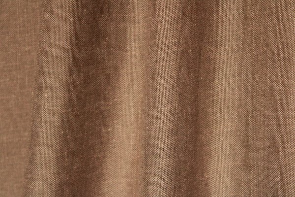 Sfeerfoto van de taupek leurige inbetween gordijnen met linnen look uit de Saphira Light collectie van Okika, soepel hangend en zacht licht doorlatend voor een warme sfeer.