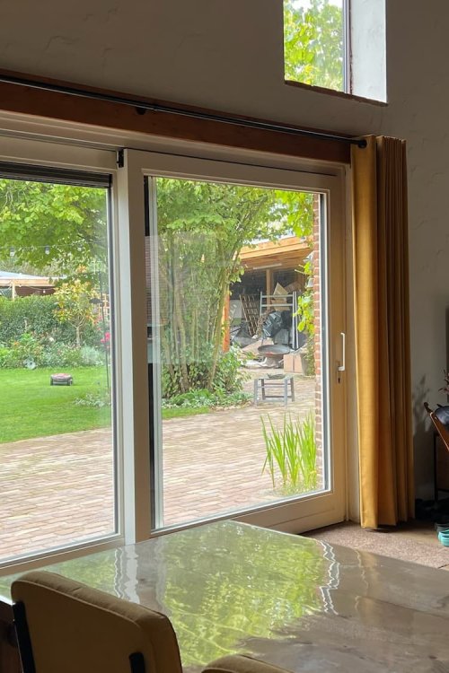 Sfeerbeeld van oker Florain gordijnen op ringen bij schuifpui in interieursetting