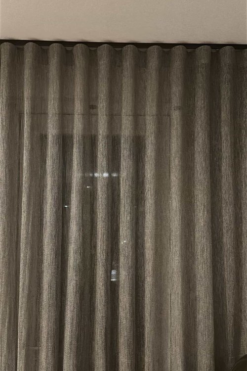 Wave plooi gordijnen van 6 cm in de stof Linea grijs, gesloten in een woonkamer bij een klant thuis, met een gelijkmatige valling over de hele breedte. golven goed zichtbaar