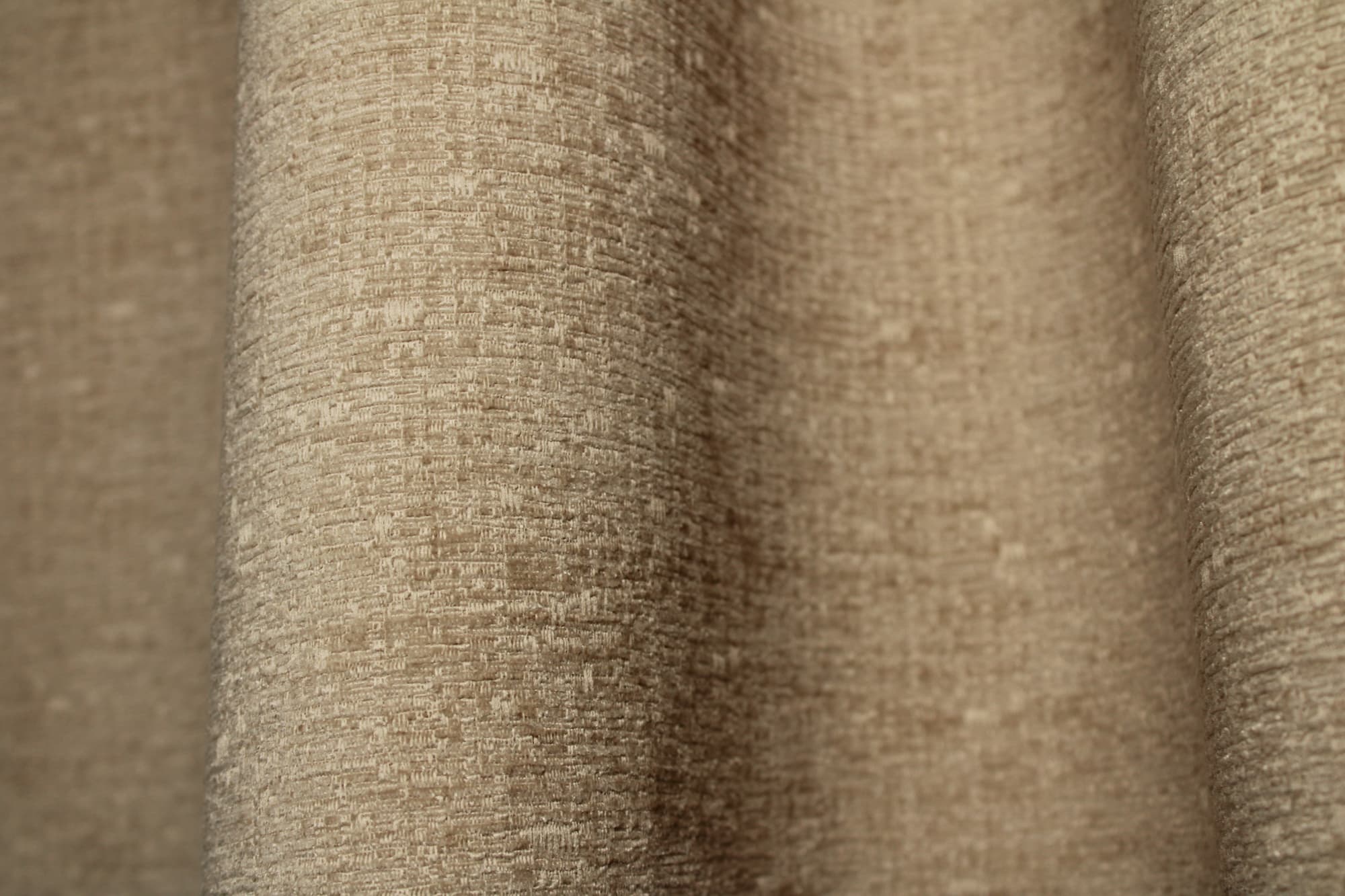 Stofpatroon van beige teddy chenille gordijnen van Okika, waarbij de plooival zichtbaar is.