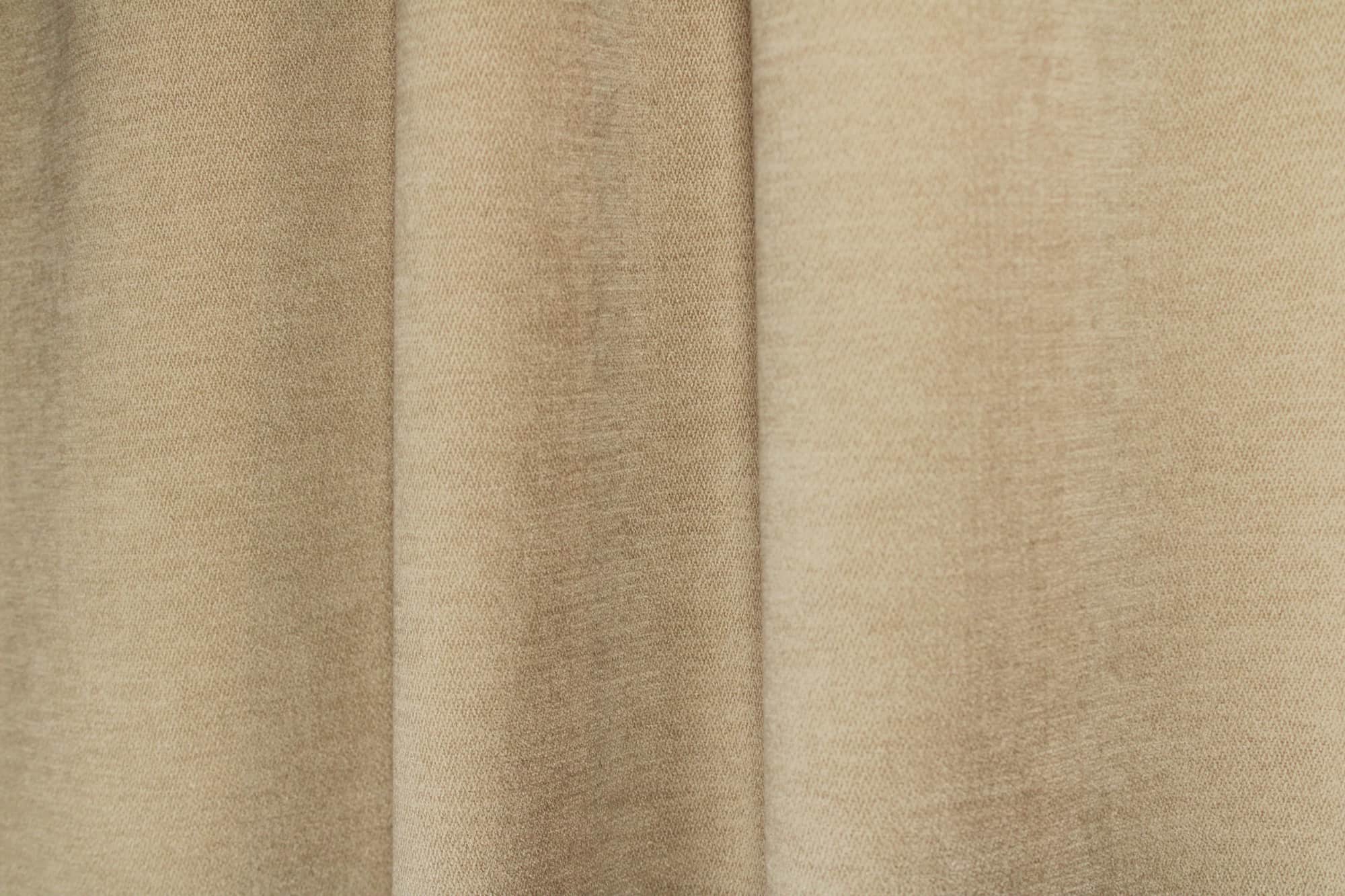 Sfeerfoto van chenille gordijnen in het creme van Okika, hangend in de plooi.