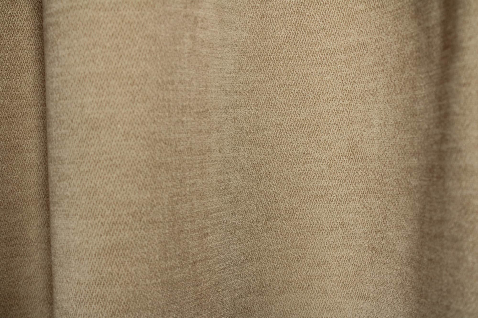 Stofdetails van crèmekleurige chenille gordijnen van Okika, met zicht op de chenille structuur.