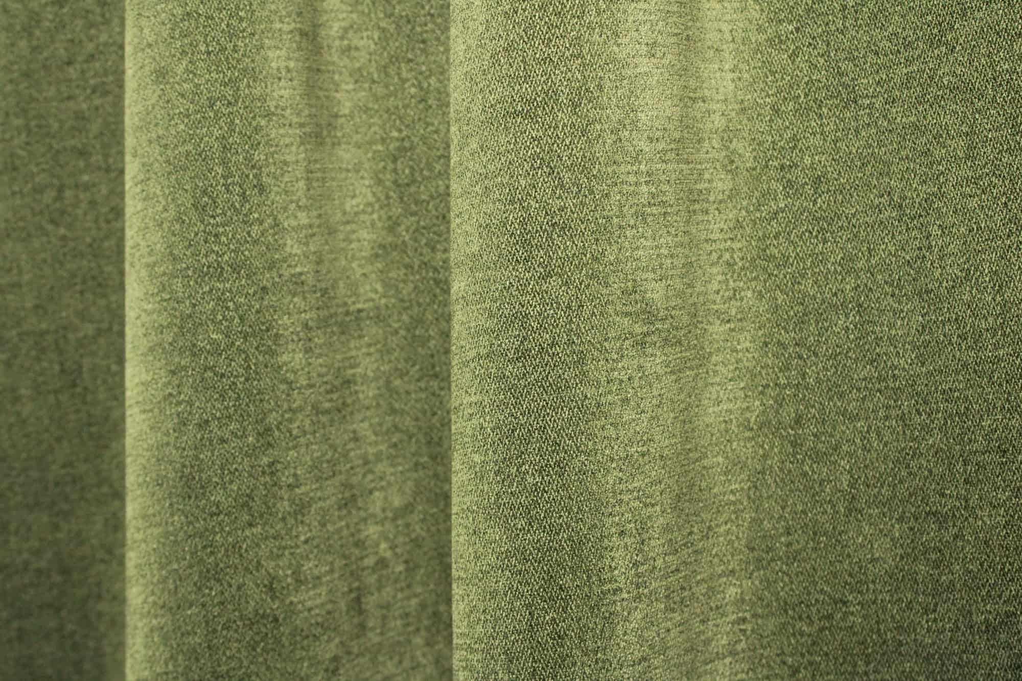 Sfeerfoto van groene chenille gordijnen van Okika, getoond in de plooi, met een rustige uitstraling en zachte lichtinval in het interieur.