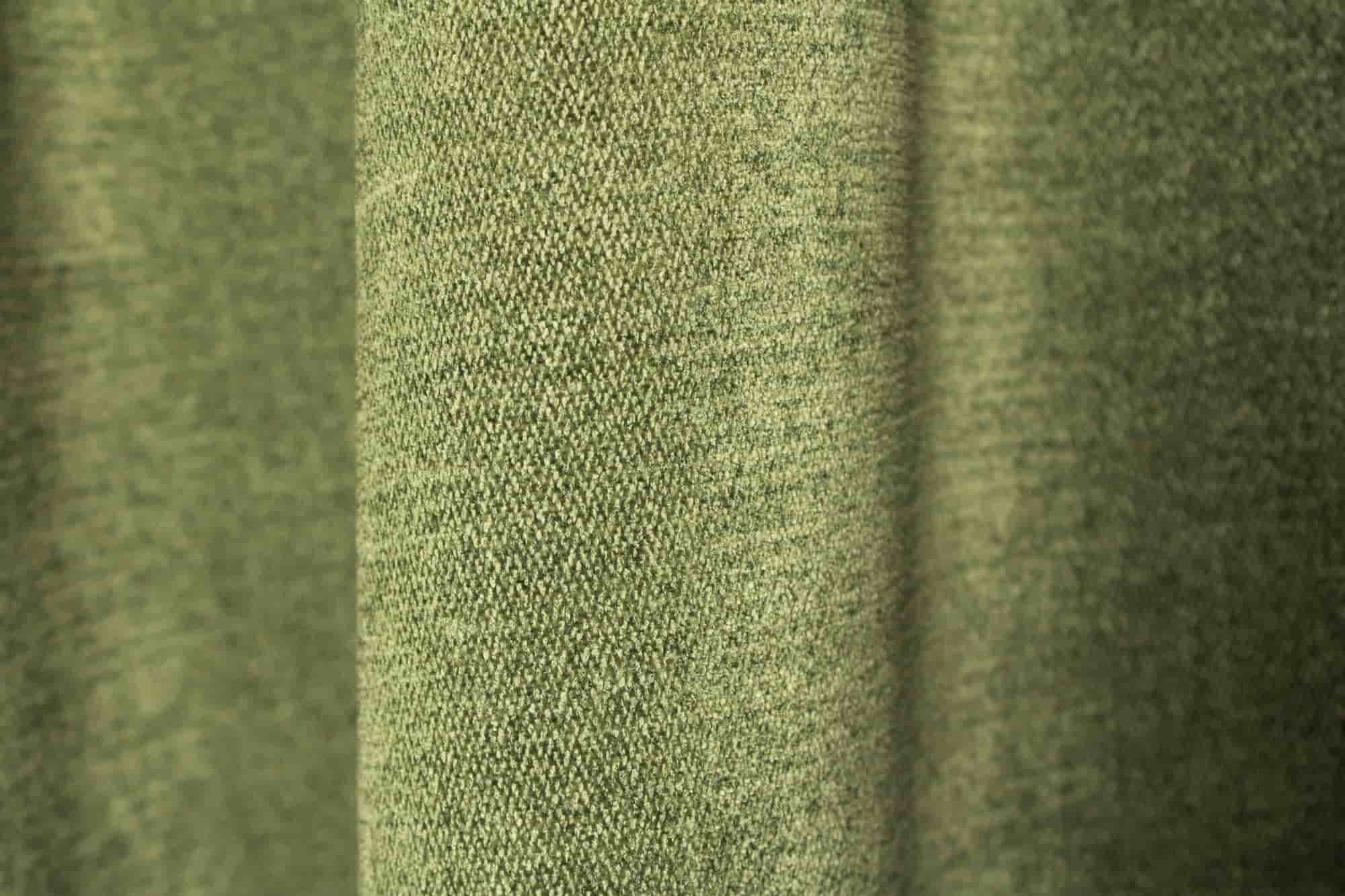 Stofpatroon van groene chenille gordijnen van Okika, met zicht op de stof in de plooi en een gelijkmatige, zachte structuur.
