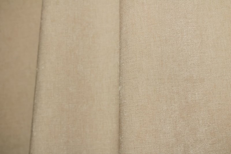 Ivoor chenille gordijnen in een lichte interieursetting, met de zachte krijtstructuur duidelijk zichtbaar.