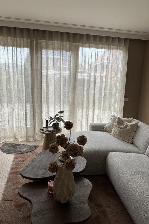 inbetween linnen gordijn Maison in crème, opgehangen als wavegordijn bij een klant in de woonkamer. De natuurlijke linnen structuur en zachte plooien zorgen voor een rustige, lichte sfeer met warm daglicht.