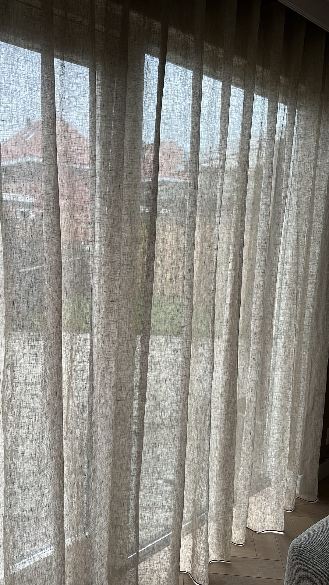 close-up van een inbetween linnen gordijn Maison in crème bij een klant in de woonkamer. Het wavegordijn valt soepel en laat het licht zacht door, wat de ruimte een rustige, natuurlijke sfeer geeft.