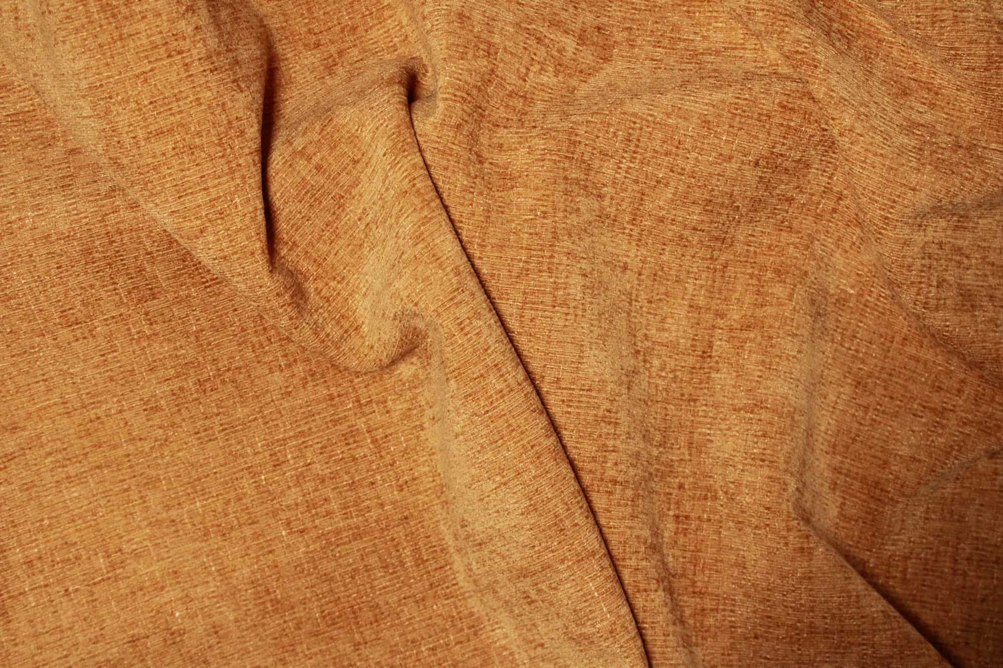tailopname bij natuurlijk licht. Stofstructuur van okergele teddy chenille gordijnen van Okika, gefotografeerd op korte afstand.