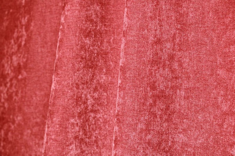 Sfeer foto van oudroze chenille gordijnen in een plooi, met de zachte krijtstructuur subtiel zichtbaar.