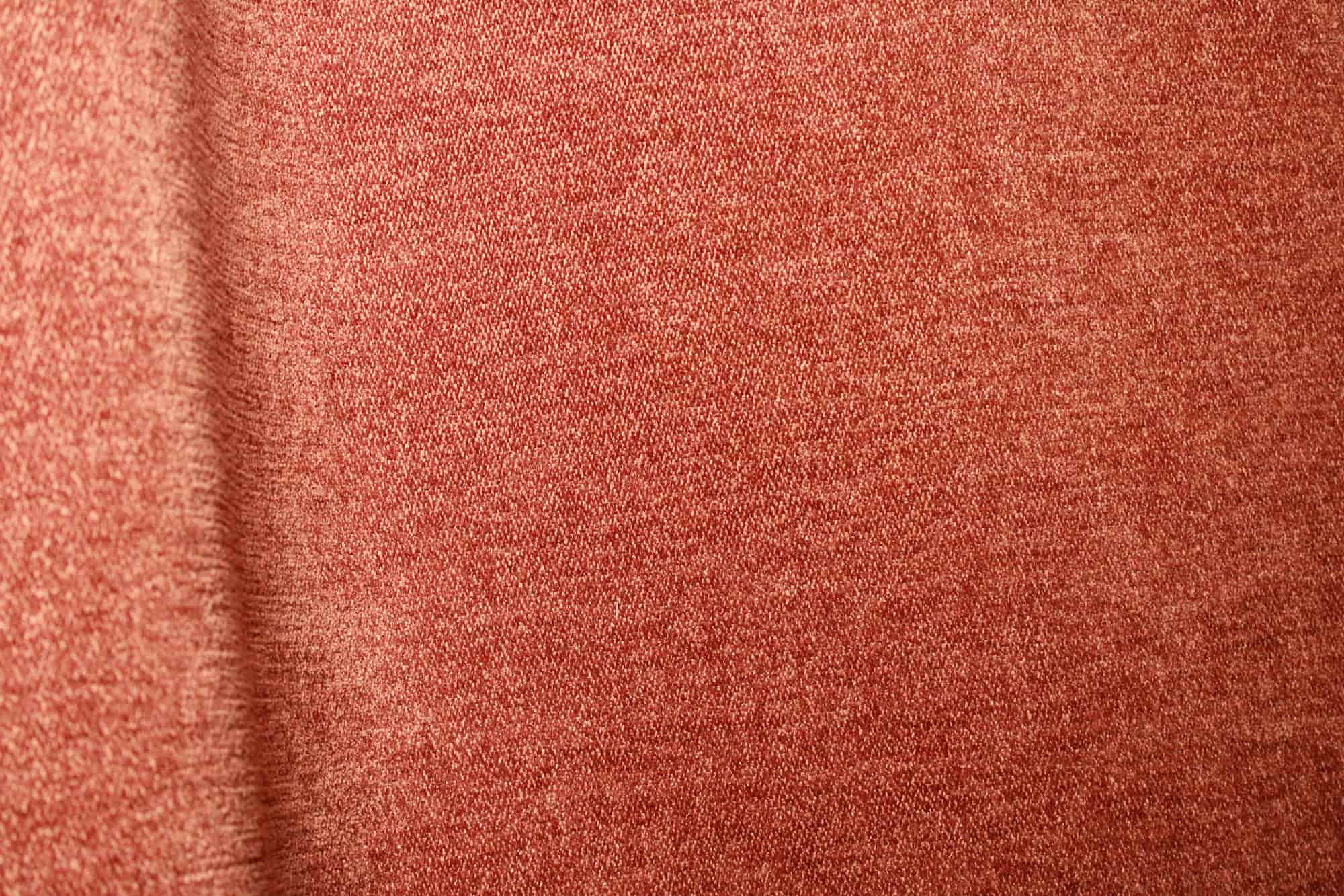 Stofdetails van roestkleurige chenille gordijnen van Okika, met zichtbare zachte structuur en warme kleurnuance bij natuurlijk licht.