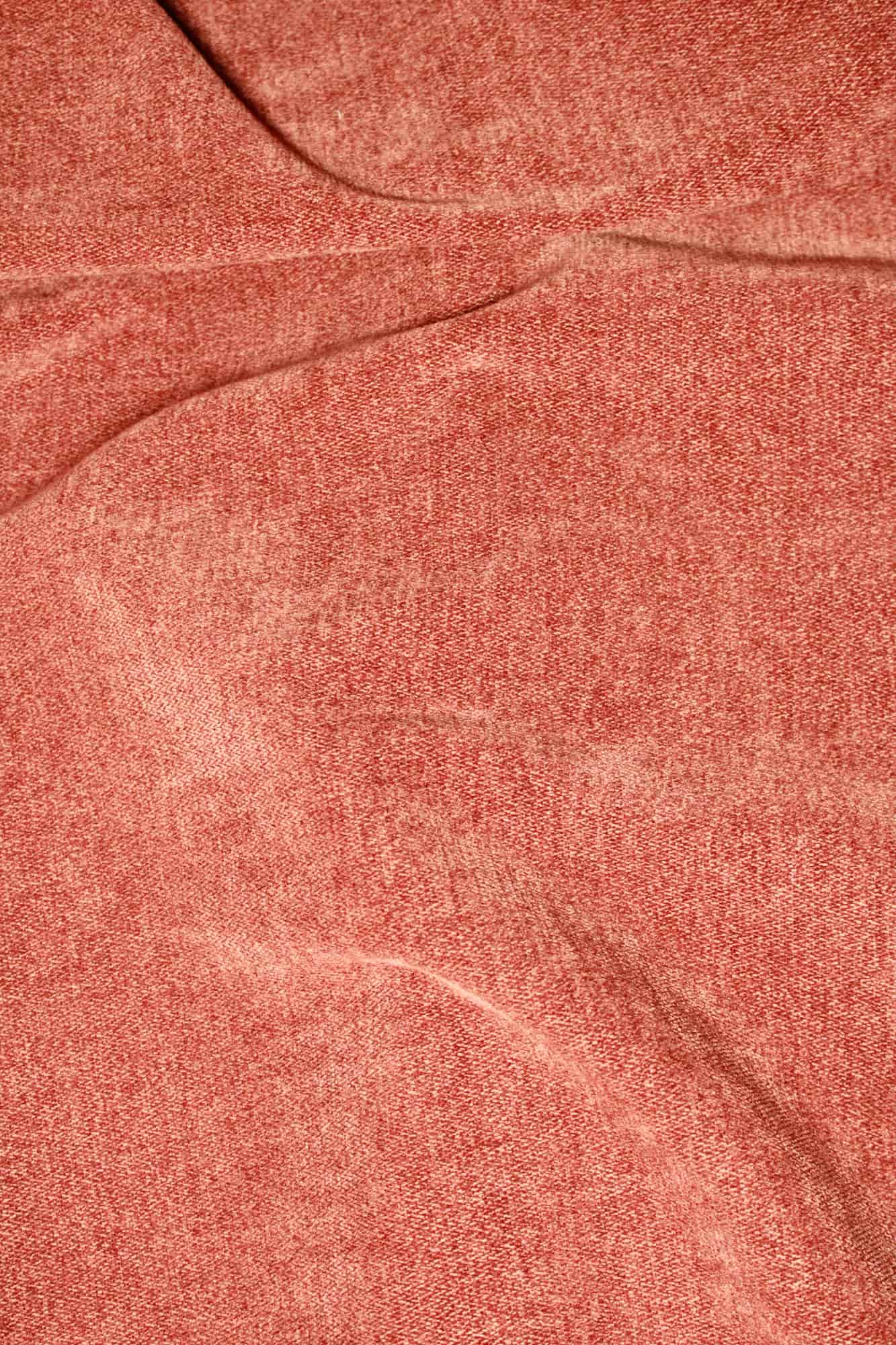 Stofstructuur van roestkleurige chenille gordijnen van Okika, van dichtbij gefotografeerd met duidelijk zicht op de visgraat weving bij daglicht.