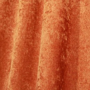 Sfeerfoto van roestkleurige chenille gordijnen in een plooi, met de zachte krijtstructuur subtiel zichtbaar