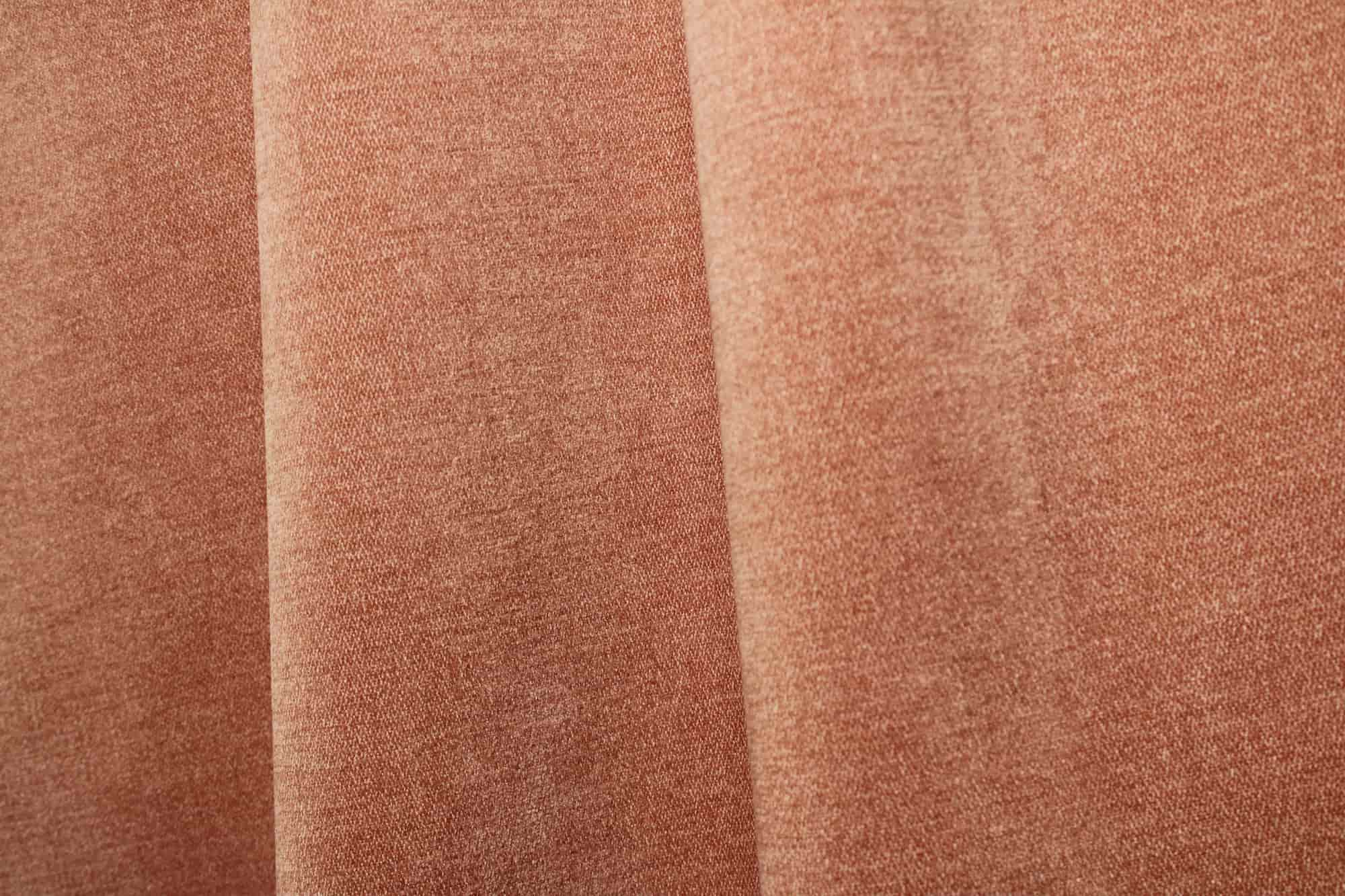 Sfeerfoto van zachtroze chenille gordijnen van Okika, getoond in de plooi, met een zachte en rustige uitstraling bij natuurlijk licht in het interieur.