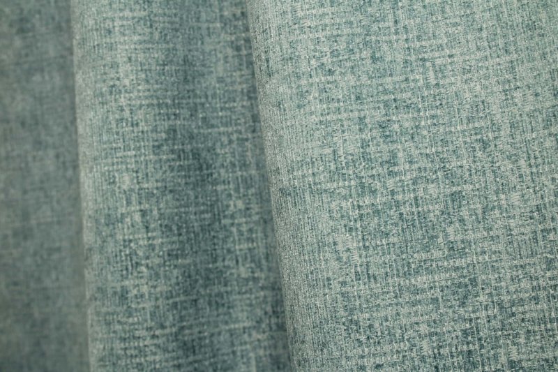 Sfeerfoto van blauwe teddy chenille gordijnen van Okika, getoond in de plooi, met een zachte en rustige uitstraling bij natuurlijk licht in het interieur.