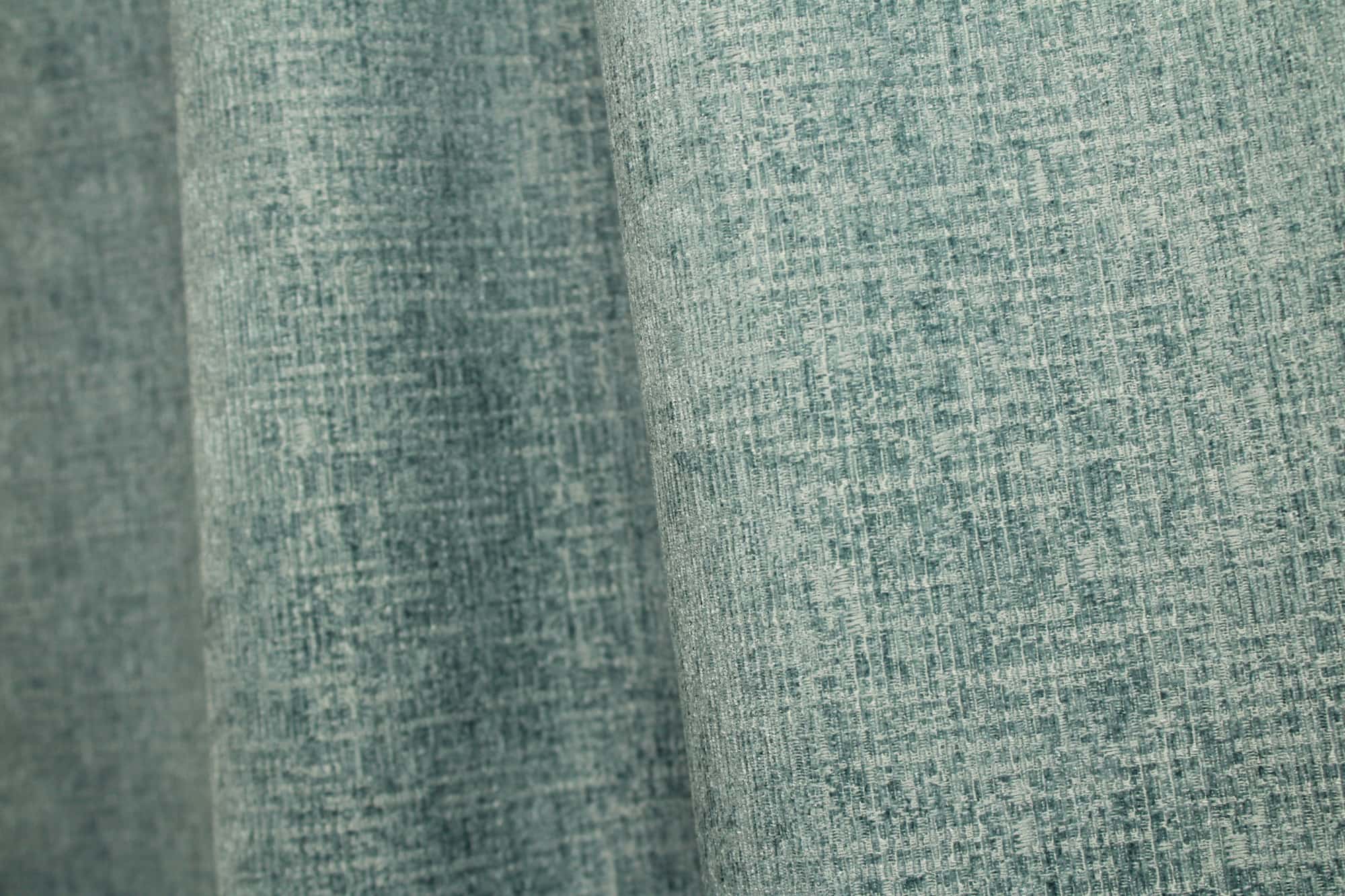 Sfeerfoto van blauwe teddy chenille gordijnen van Okika, getoond in de plooi, met een zachte en rustige uitstraling bij natuurlijk licht in het interieur.