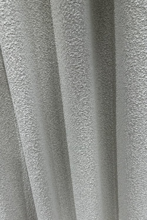 boucle-gordijnen-waveplooi-okika-woonkamerklant-closeupgordijn (2) Close up van bouclé gordijnen in waveplooi in de woonkamer van een klant, sfeerfoto met zicht op de stofstructuur