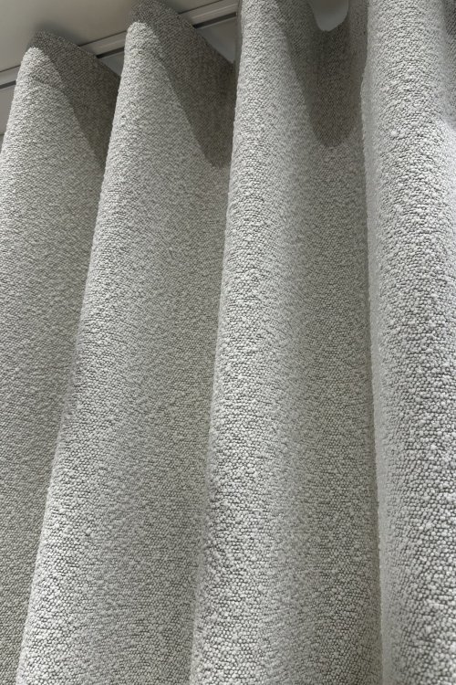 boucle-gordijnen-waveplooi-okika-woonkamerklant-sfeer (1) Sfeerfoto van bouclé gordijnen met waveplooi van Okika, recent afgeleverd bij een klant en hangt in een woonkamer.