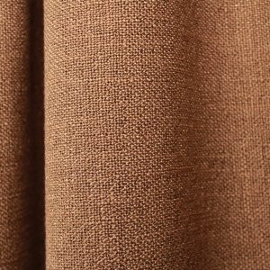 Stofdetails van bruine gordijnen uit de Boucloir collectie JC2598, close-up van de semilichtdoorlatende stof waarbij de structuur en het materiaal zichtbaar zijn in de plooien.