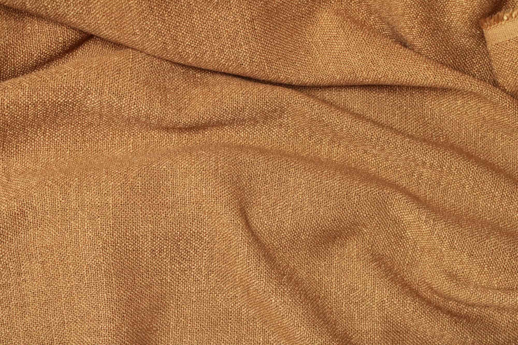 Stofstructuur van cognac gordijnen uit de Boucloir collectie JC2602, close-up van de semilichtdoorlatende weving met zichtbaar structuurdetail in daglicht.