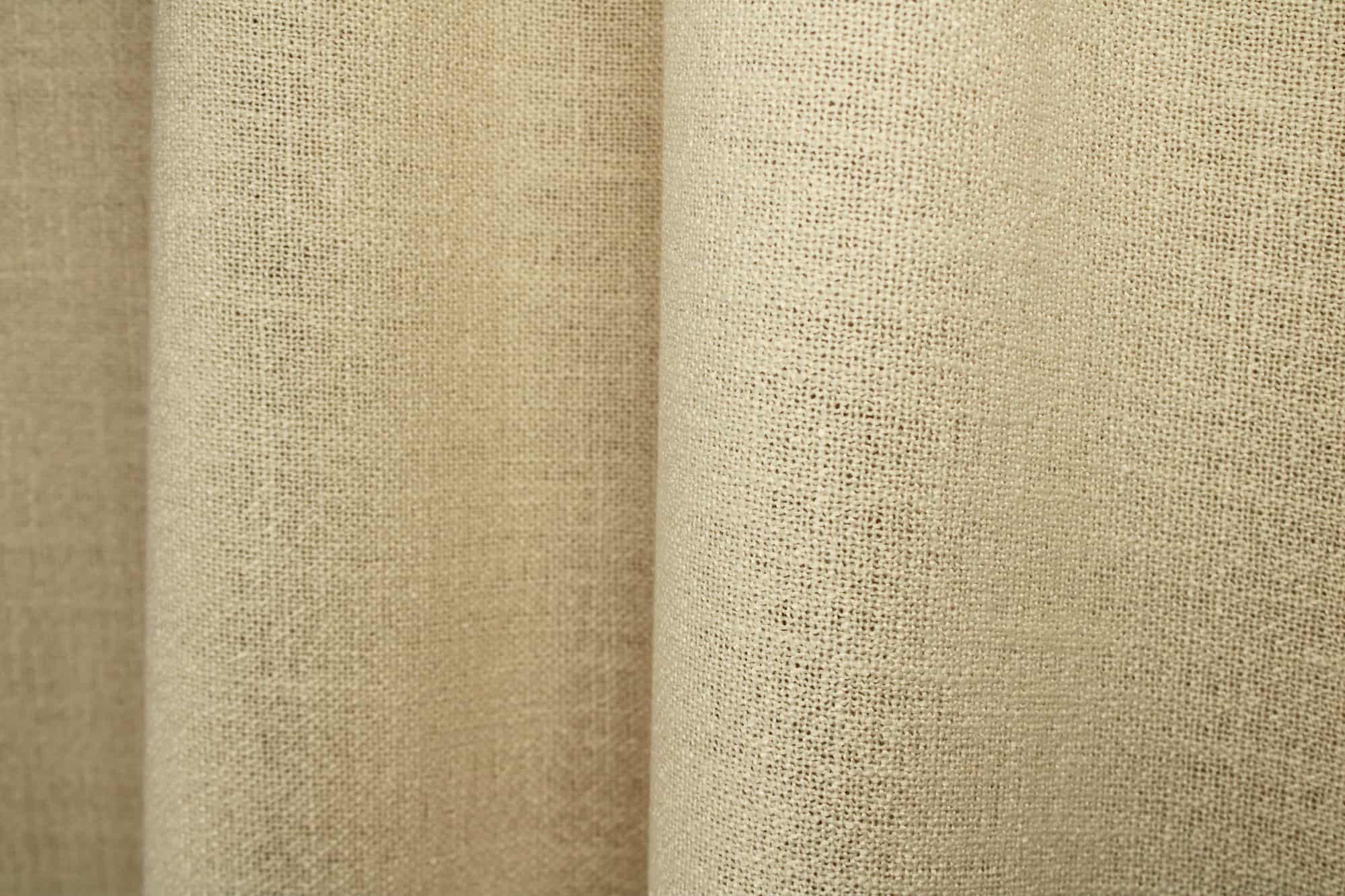 Crèmekleurige gordijnen uit de Boucloir collectie JC2603 in een licht interieur, semilichtdoorlatende stof met zachte lichtinval. Dit is een sfeerbeeld waarbij de gordijnen in plooien zijn gefotografeerd