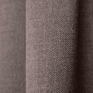 Close up van de stof van donker taupe gordijnen uit de Boucloir collectie JC2591, met zichtbare overtwist garen in de semilichtdoorlatende stof.