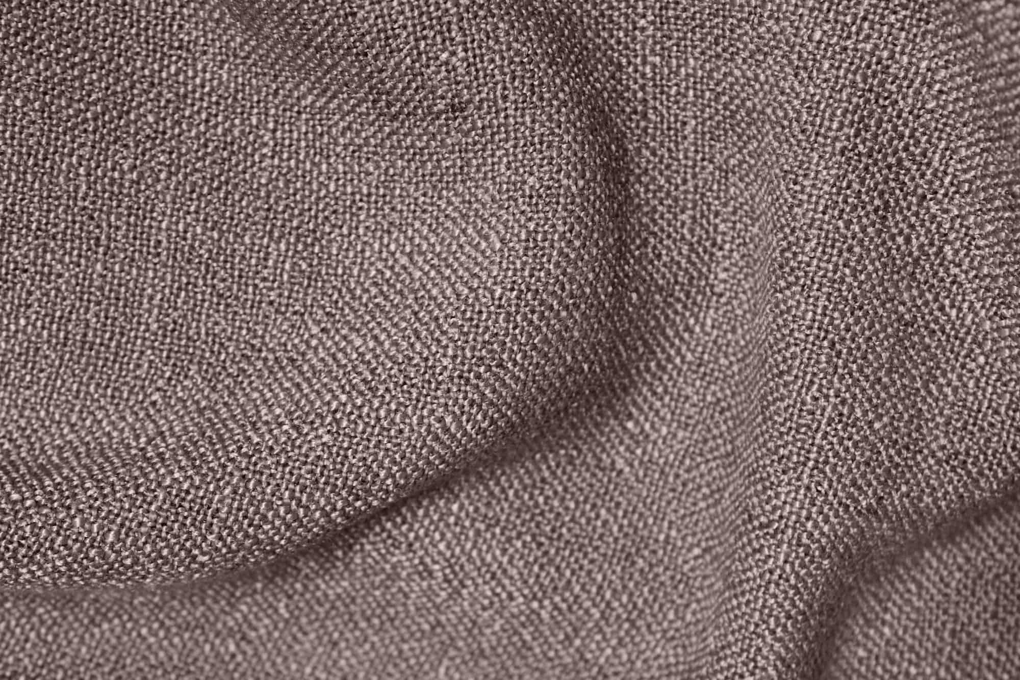 Detail van de stofstructuur van donker taupe gordijnen uit de Boucloir collectie JC2591, met een duidelijke overtwist garen weving