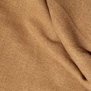 Structuurdetail van honingkleurige gordijnen uit de Boucloir collectie JC2608, waarbij de grove weving en het natuurlijke licht samen het karakter van de stof laten zien.
