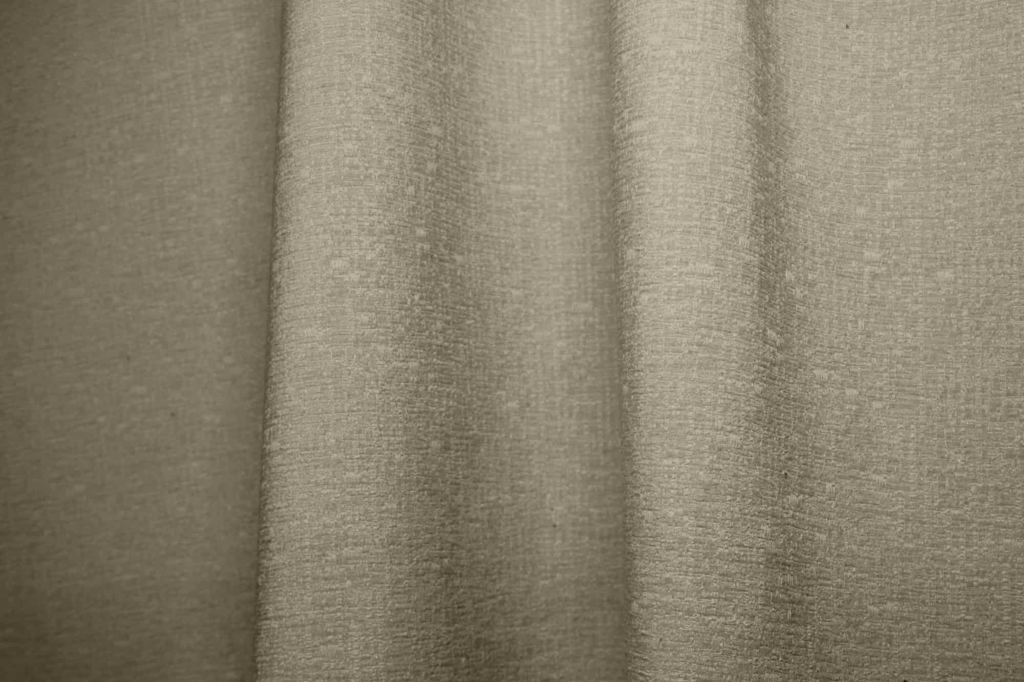 Sfeerfoto van ivoorkleurige teddy chenille gordijnen van Okika, waarbij de gordijnen in de plooi hangen.