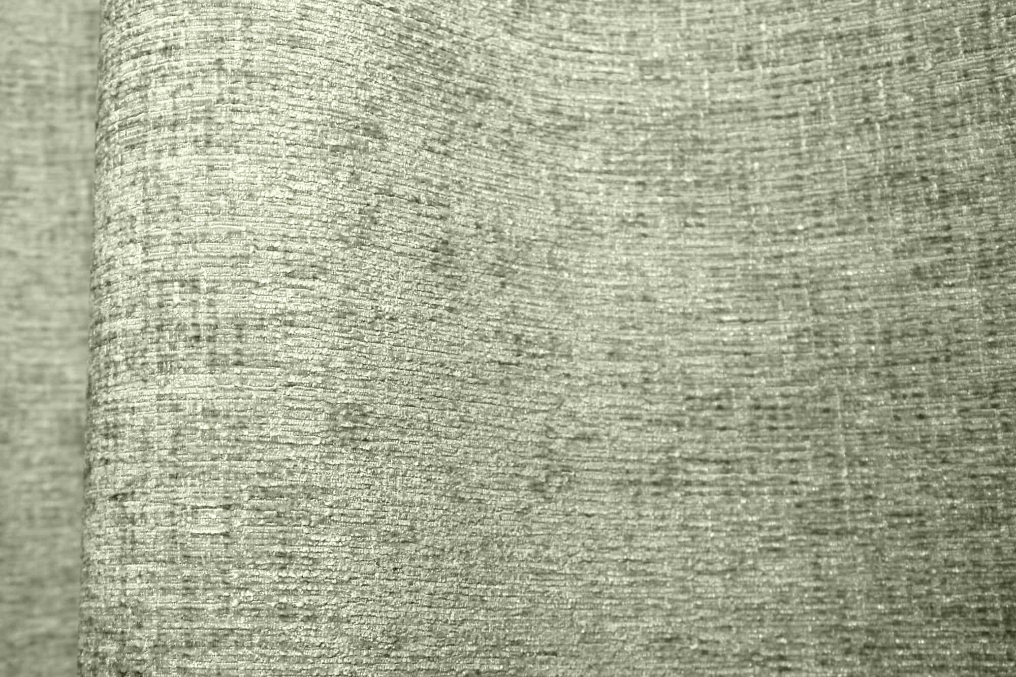 Stofdetails van mintgroene teddy chenille gordijnen van Stofpatroon van mintgroene teddy chenille gordijnen van Okika, met de nadruk op de plooival en het rustige, egale teddykarakter van de stof bij natuurlijk licht.