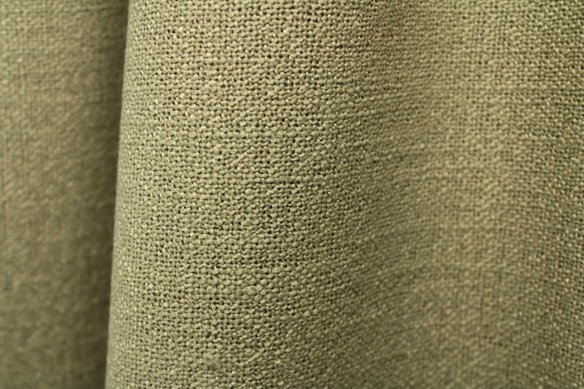 Close up van pistachekleurige gordijnstof uit de Boucloir collectie JC2609, waarbij de overtwist garen en lichte transparantie van de stof goed zichtbaar zijn.