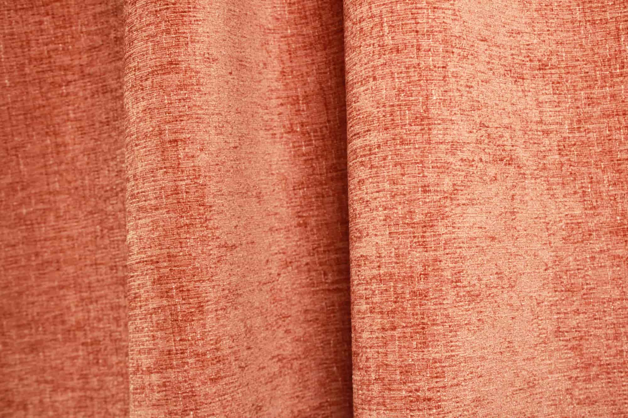 Sfeerfoto van roestkleurige teddy chenille gordijnen van Okika, getoond in de plooi, met een warme en zachte uitstraling bij natuurlijk licht in het interieur.