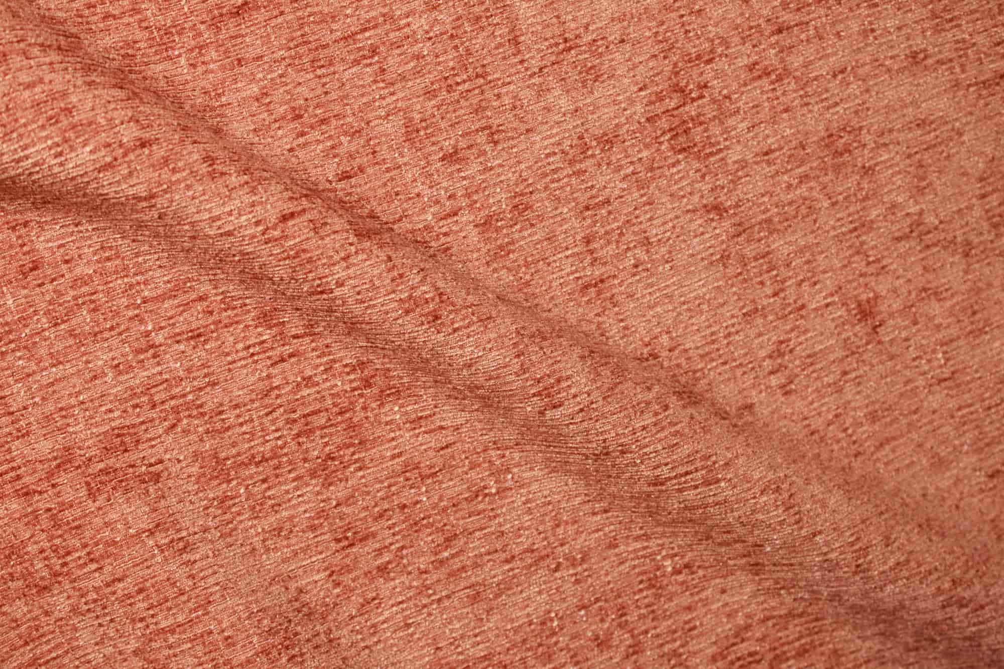 Stofstructuur van roestkleurige teddy chenille gordijnen van Okika, van dichtbij gefotografeerd met duidelijk zicht op de volle, zachte weving bij daglicht.