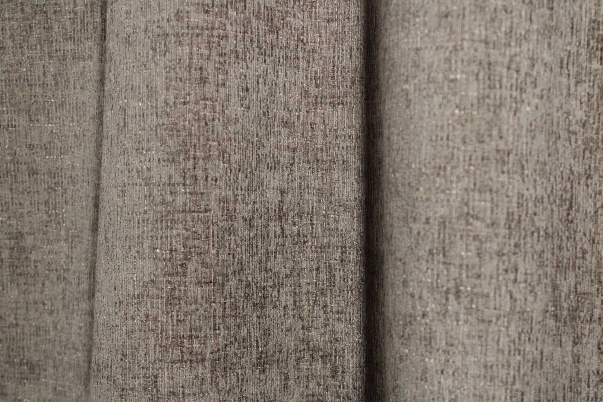 Sfeerfoto van taupekleurige teddy chenille gordijnen van Okika, getoond in de plooi, met een rustige en warme uitstraling.