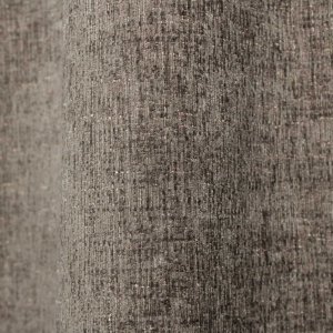 Stofpatroon van taupekleurige teddy chenille gordijnen van Okika, waarbij de stof in de plooi een gelijkmatige structuur laat zien bij daglicht.