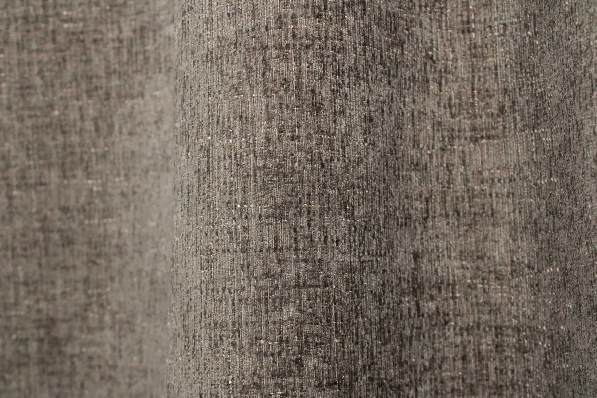 Stofpatroon van taupekleurige teddy chenille gordijnen van Okika, waarbij de stof in de plooi een gelijkmatige structuur laat zien bij daglicht.