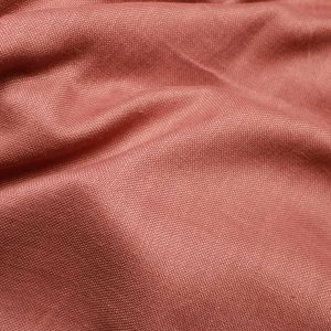 Inbetween gordijnen in terrarode kleur uit de Linoire collectie, stofstructuur close-up van het gordijn in zachte plooien.